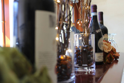 Wine bottles and glass vases with string lights on a polished wood bar