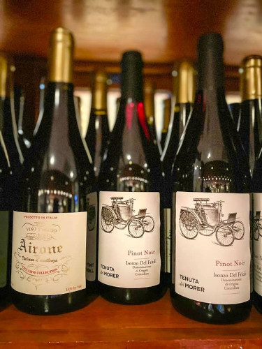 Rows of Italian red wine bottles, including Airone and Pinot Noir, on a shelf