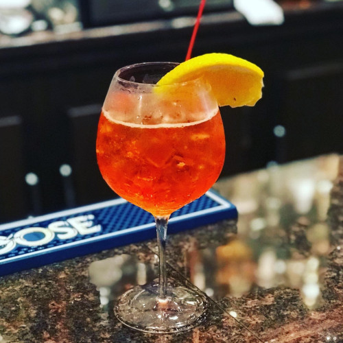Orange spritz cocktail with ice and an orange slice on a granite bar