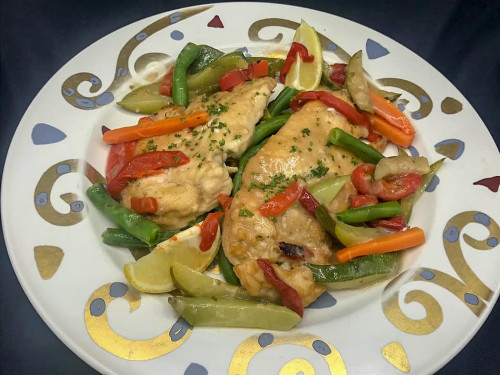 Chicken cutlets with green beans, red peppers and lemon on a decorative plate