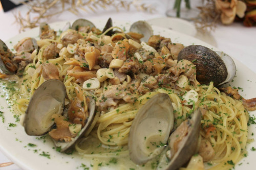 Thin spaghetti with open clams in a garlicky white wine sauce, topped with parsley