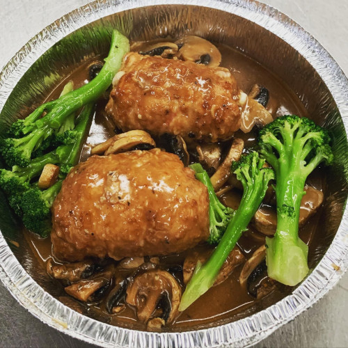Two glazed stuffed meat rolls with broccoli and mushrooms in a foil pan