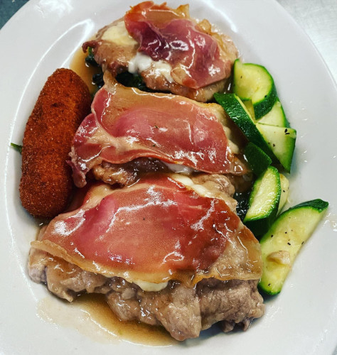 Cutlets topped with prosciutto and melted cheese, with sliced zucchini and a fried croquette