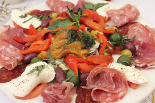Antipasto platter with cured salami, prosciutto, mozzarella, roasted peppers and olives