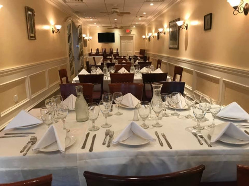 Private dining room with long white-clothed tables, wall sconces and a mounted television