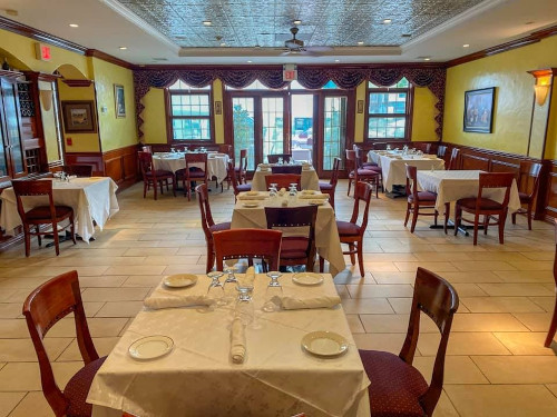Enzo's main dining room with yellow walls, tin ceiling and cream-linen tables