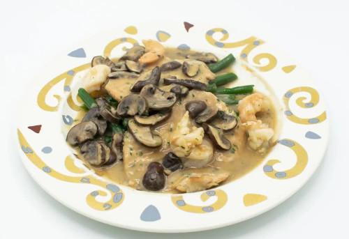 Chicken in mushroom sauce with shrimp and green beans on a decorative plate