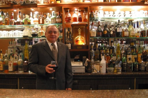 Man in a suit holding a glass of red wine at the bar