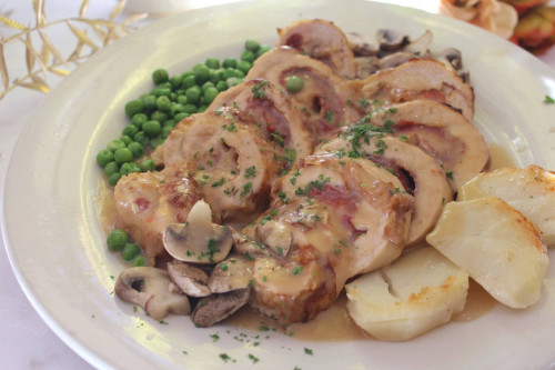Sliced stuffed rolls with mushrooms, peas and roasted potatoes in pan sauce