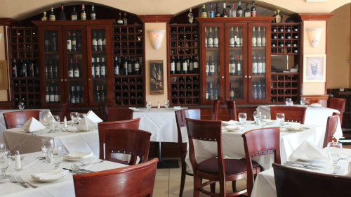 Enzo's dining room with wall cabinets of wine bottles above tables with white linens