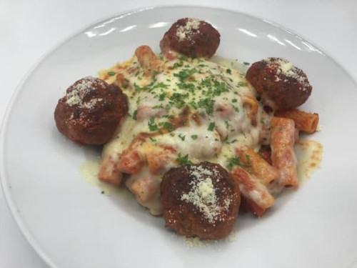 Four meatballs around baked ziti with melted mozzarella, tomato sauce and parsley